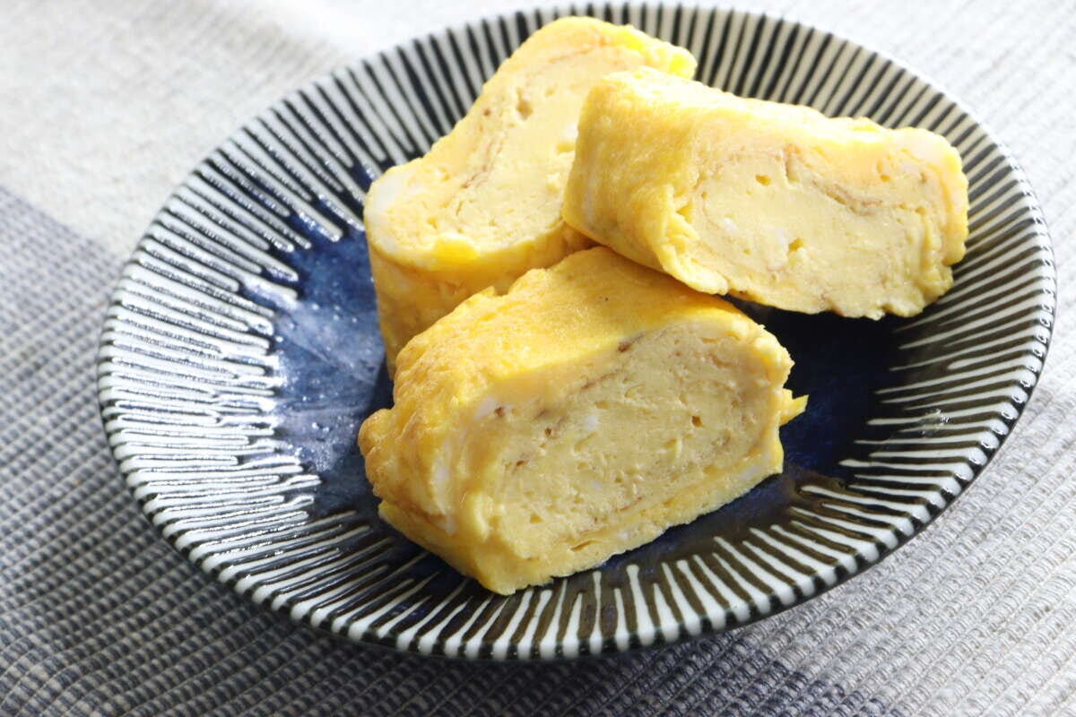 青い皿に盛り付けられた厚焼き卵3切れ 青い皿に盛り付けられた厚焼き卵3切れ